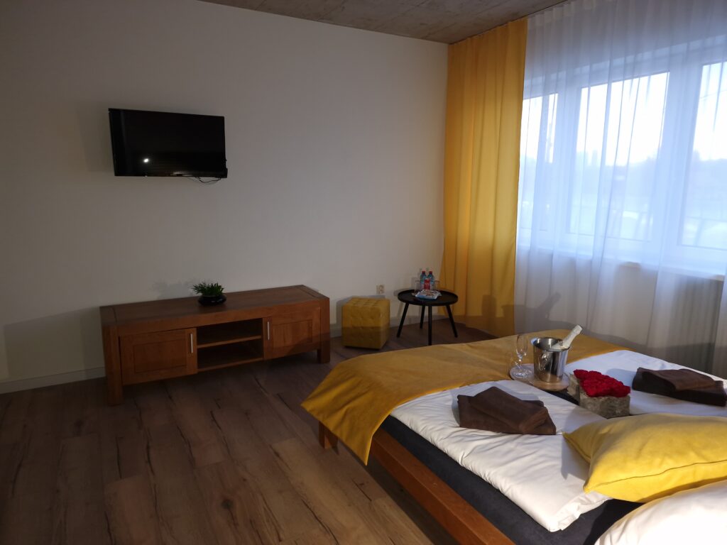 Interiér apartmánu s manželskou posteľou, TV a veľkým oknom