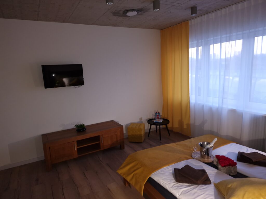 Interiér apartmánu s manželskou posteľou, TV a veľkým oknom