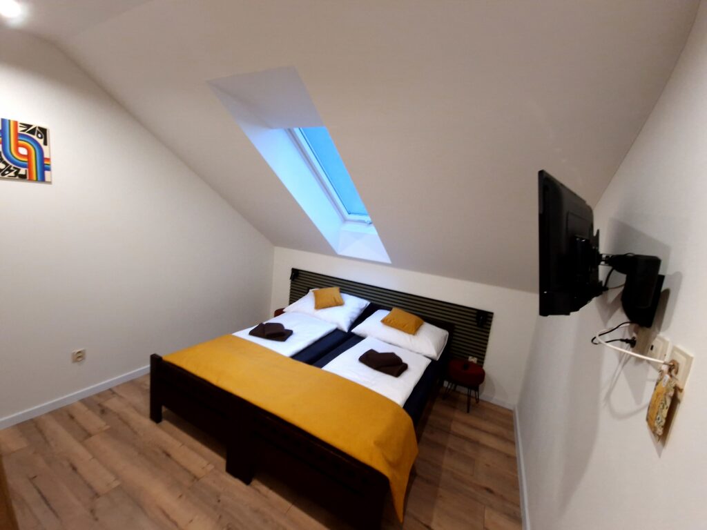 Interiér izby Standard s TV, manželskou posteľou a strešným oknom