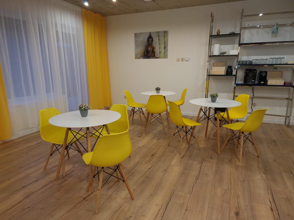 Interiér kuchyne v apartmánoch Birdhouse s tromi stolmi, deviatimi stoličkami a obrazom na stene