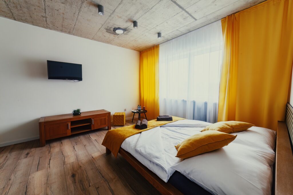 Interiér apartmánu s manželskou posteľou, TV a veľkým oknom