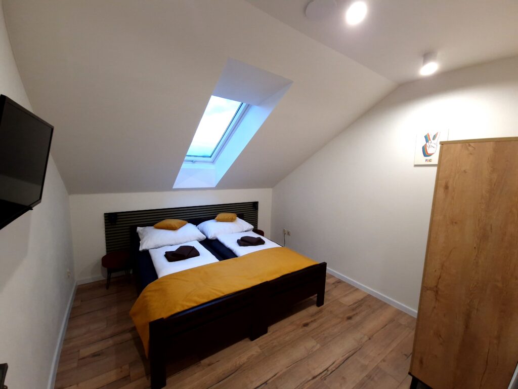 Standard room interior with TV, double bed and roof window