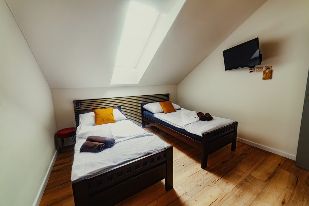 Standard room interior with two single beds, TV and roof window